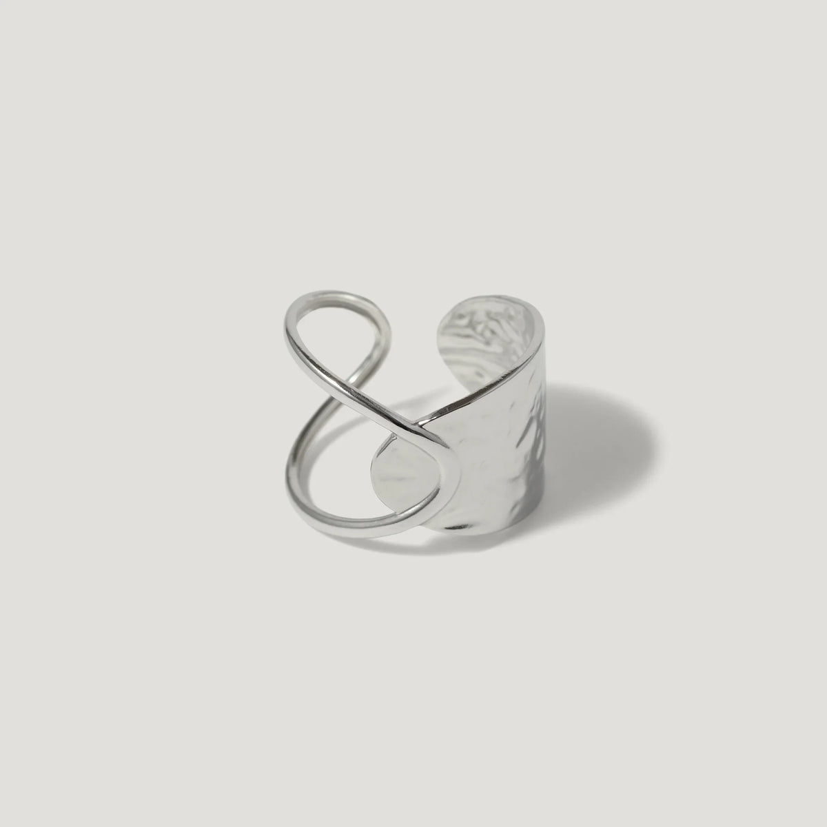 Modern sterling silver ring with open infinity design and hammered texture on white background
