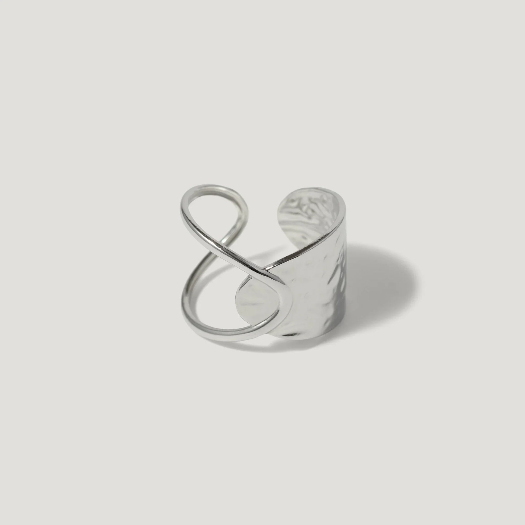 Modern sterling silver ring with open infinity design and hammered texture on white background