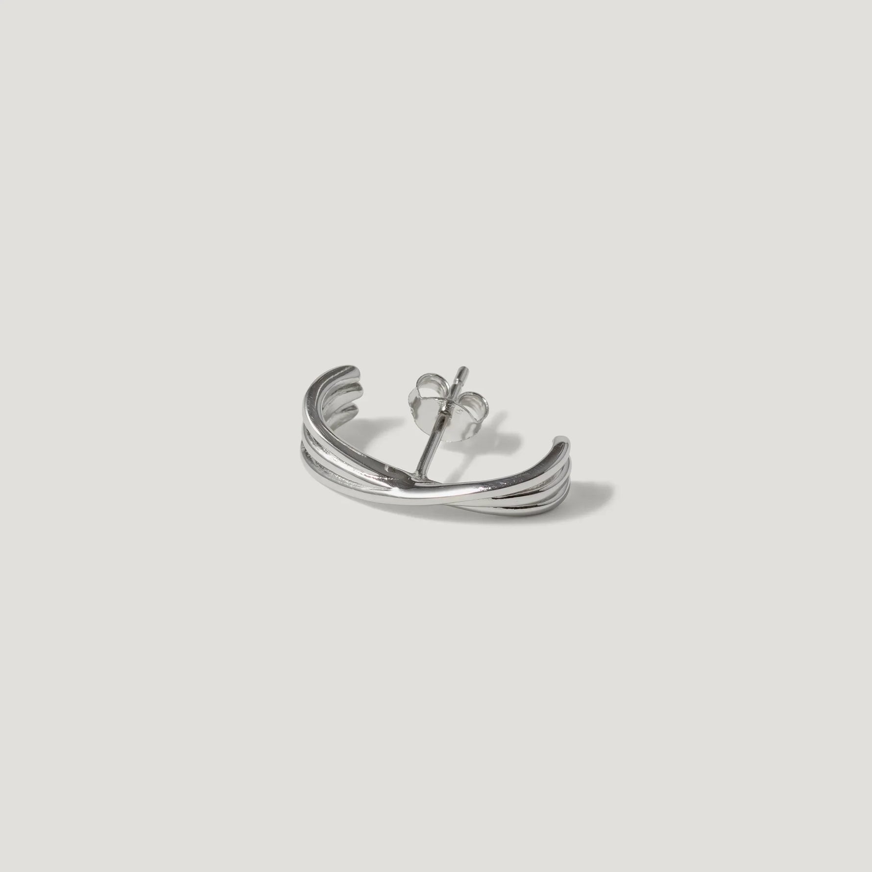 Sterling silver curved stud earring with textured grooves on a light background