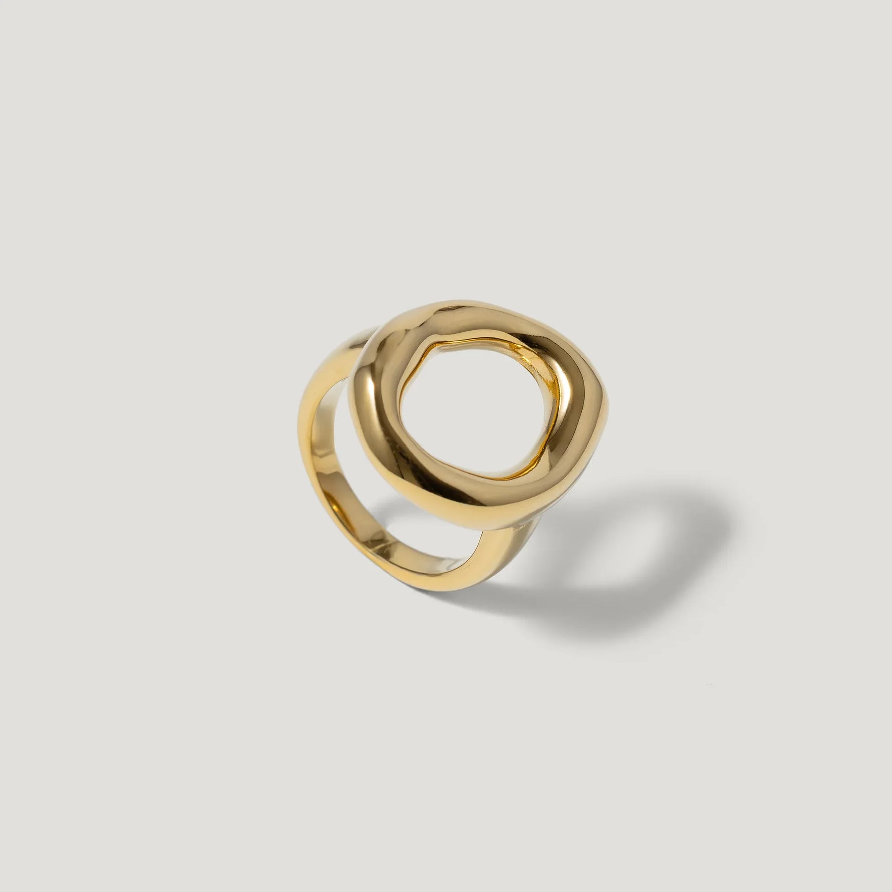 Modern gold ring with organic open circle design on a plain light background