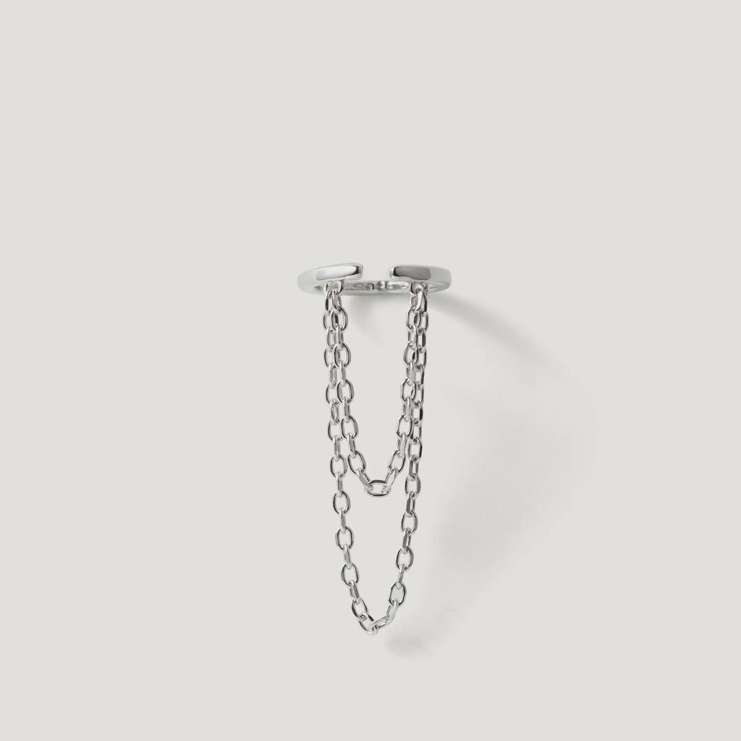 Modern silver ring with double chain detail on white background, contemporary jewelry design