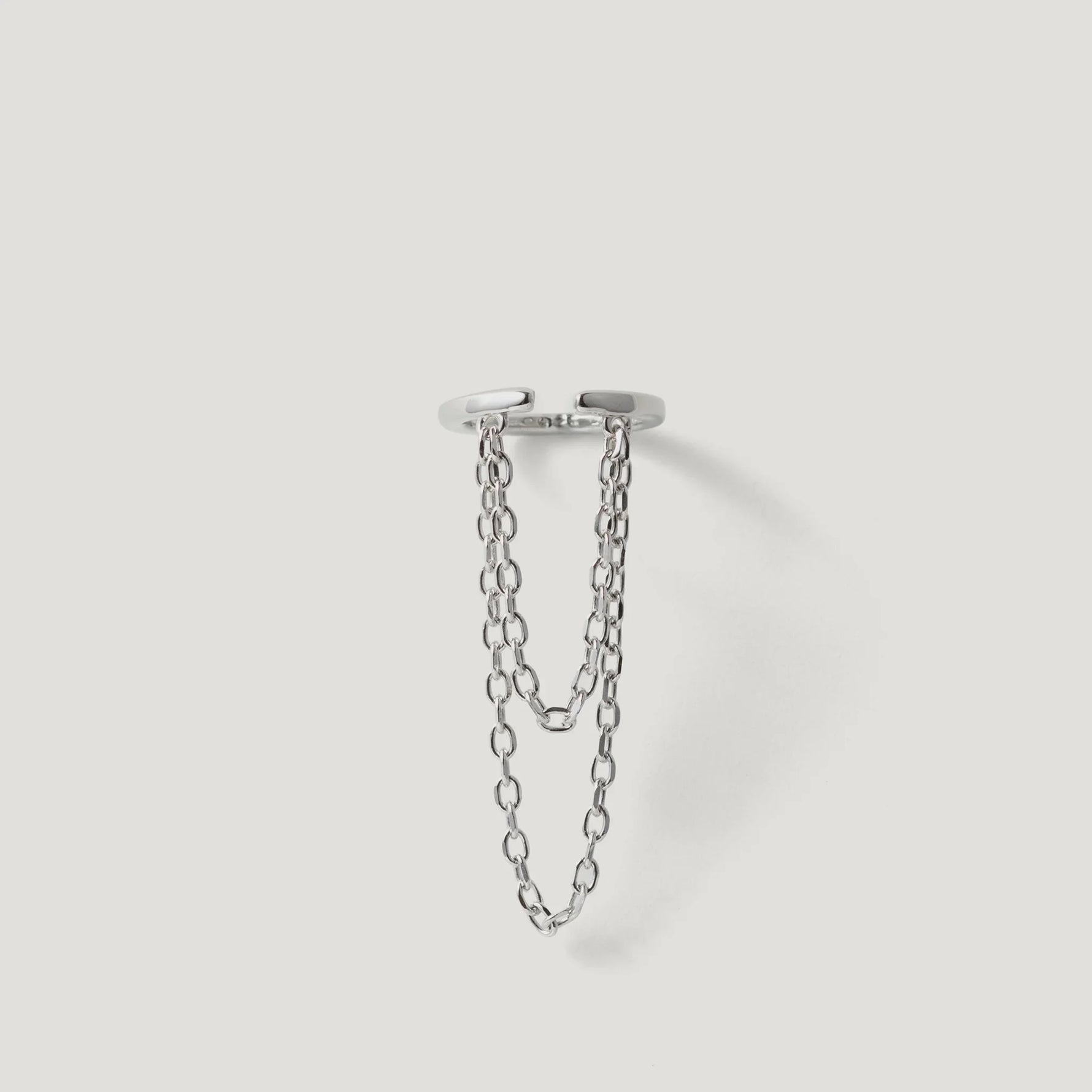 Modern silver ring with double chain detail on white background, contemporary jewelry design