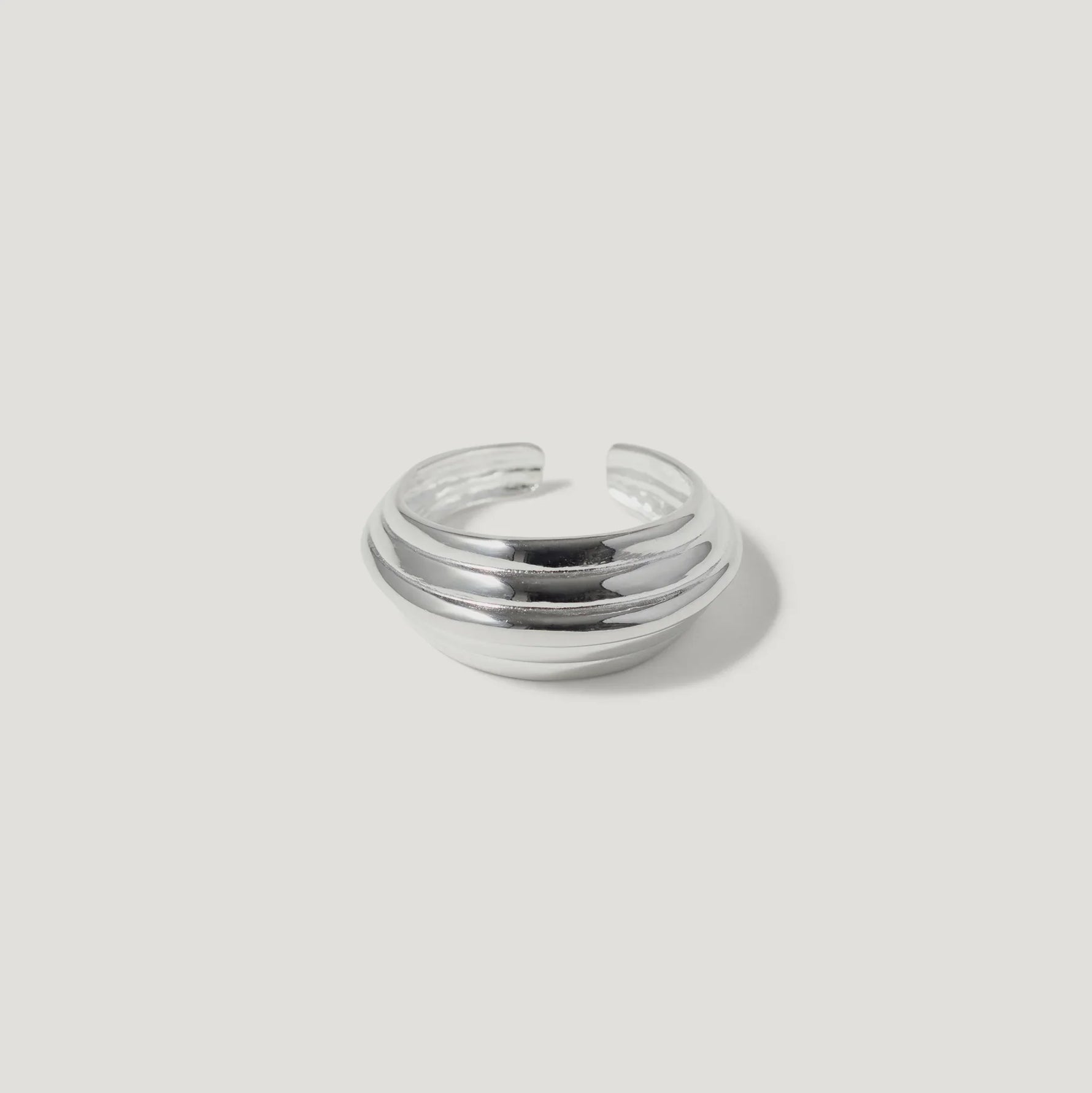 Chunky silver dome ring with layered bands on a white background