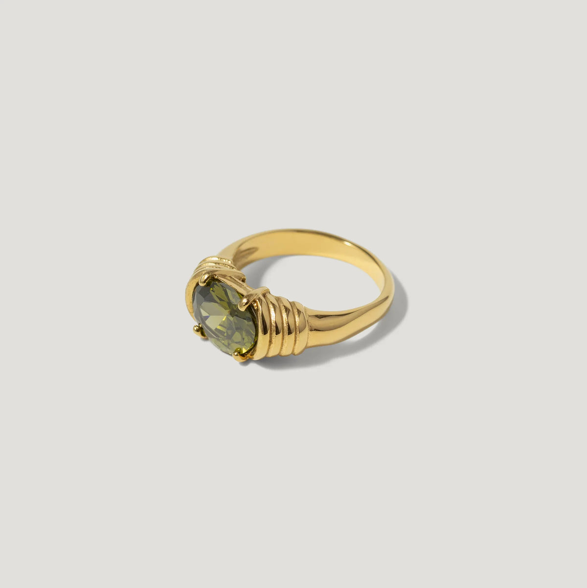 Gold ring with a round green gemstone and textured band on white background