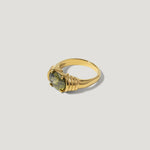 Gold ring with a round green gemstone and textured band on white background