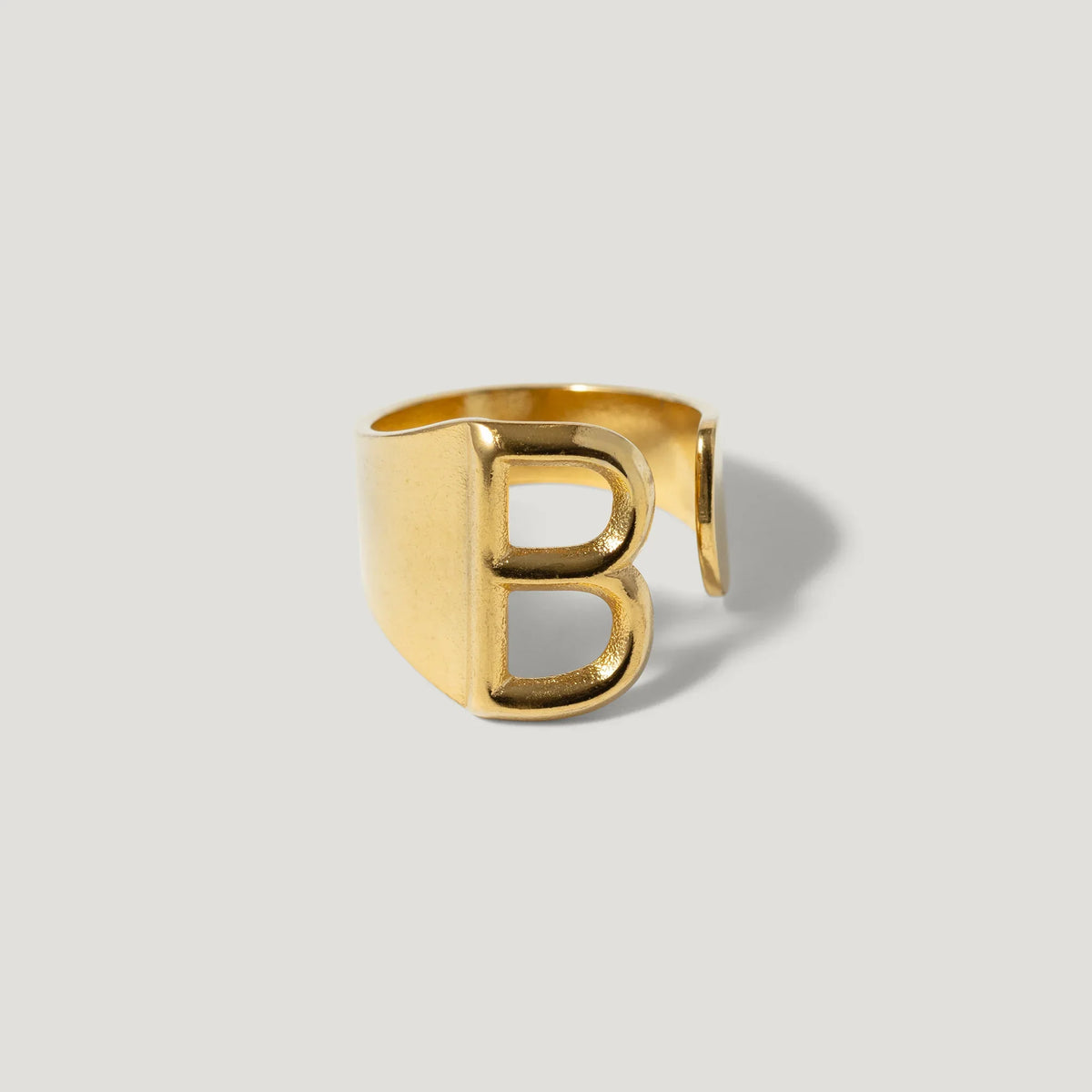 Gold letter B open band ring on plain background