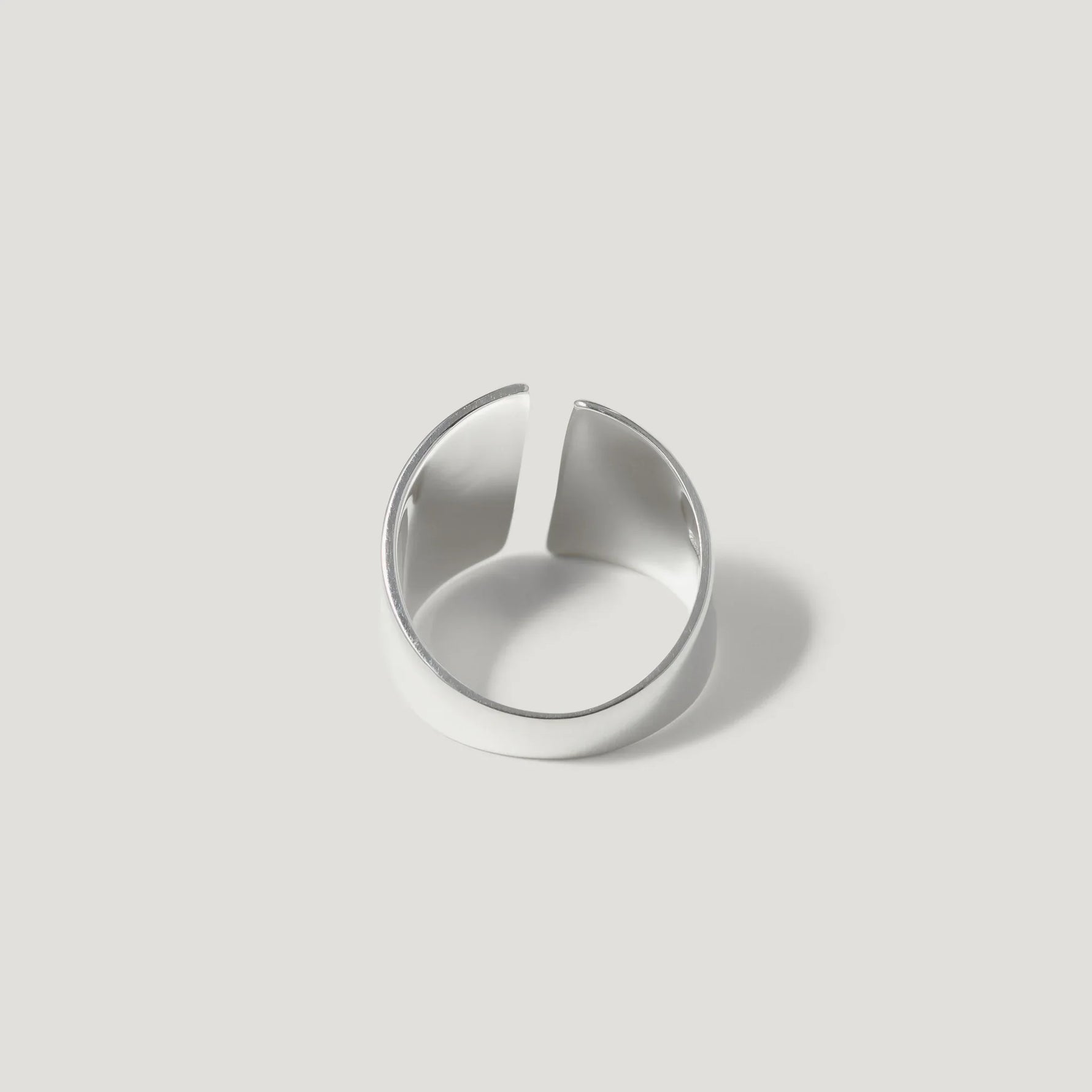Minimalist open band silver ring on a plain light background