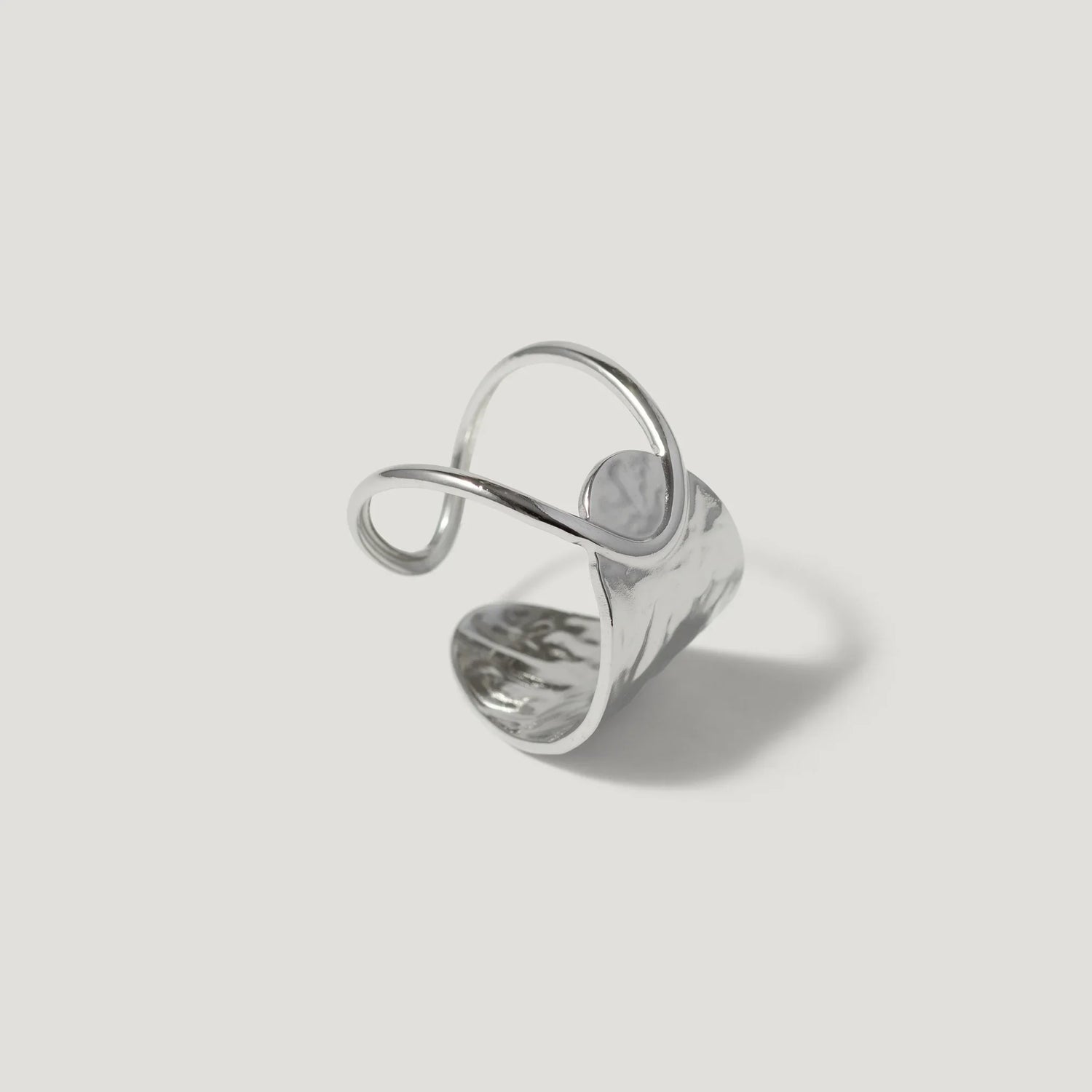 Abstract silver ring with curved, wavy design on white background