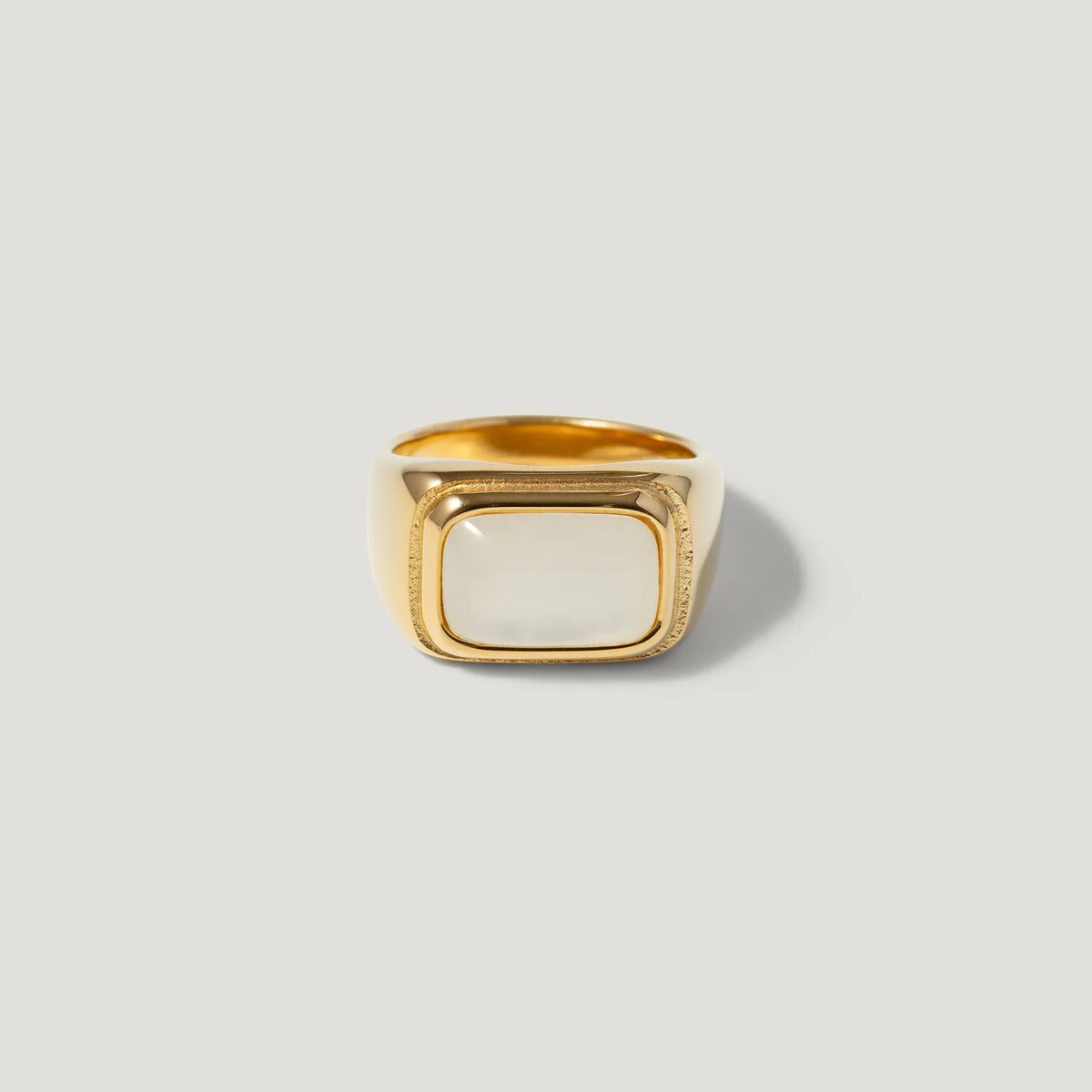 Gold signet ring with a square white stone, minimalist and modern design on plain background