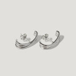 Pair of silver crescent-shaped stud earrings with layered curved design on white background