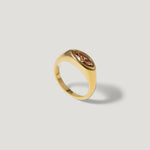 Gold ring with marquise-cut brown gemstone on light background