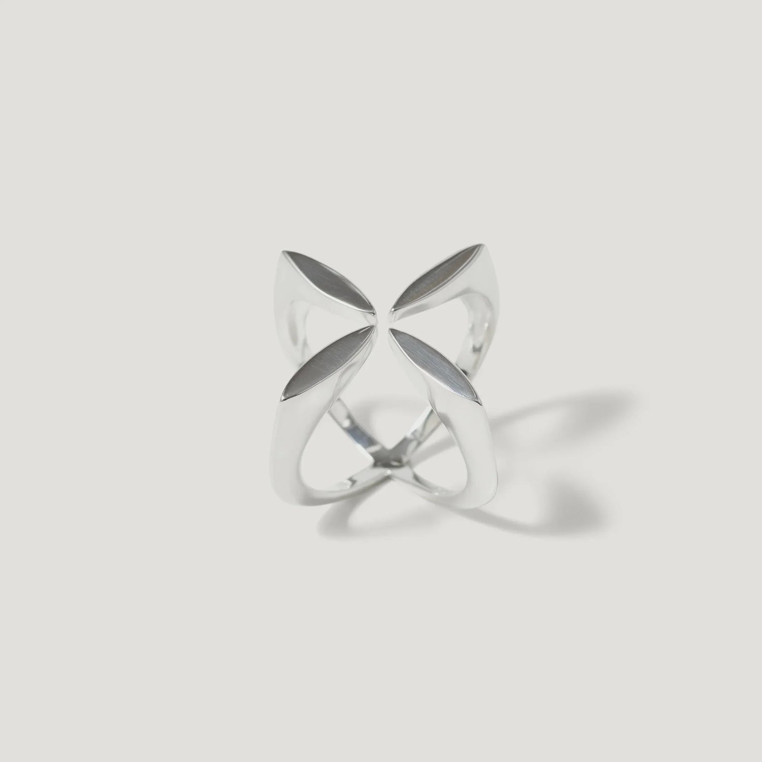 Modern silver ring with geometric, openwork petal design on white background