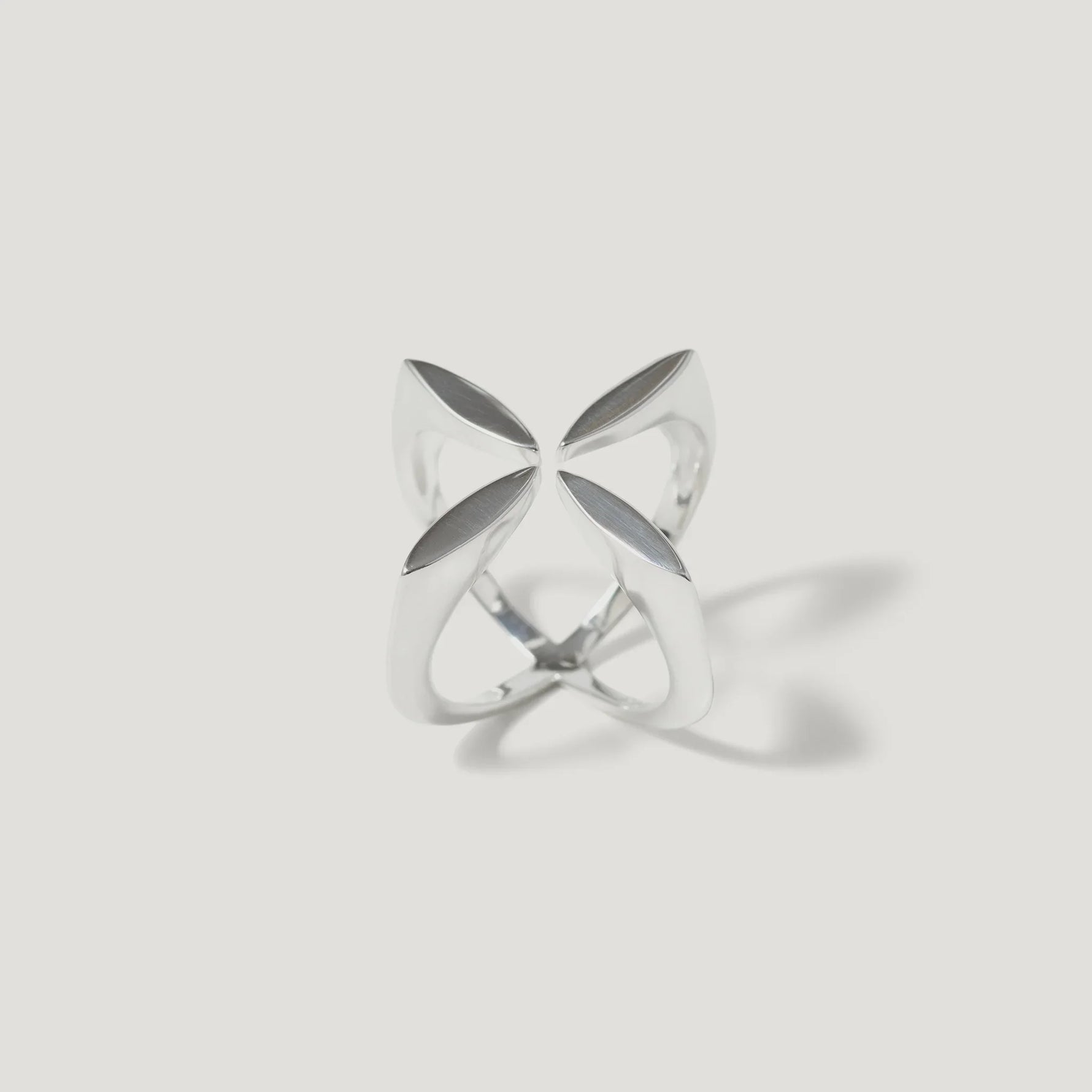 Modern silver ring with geometric, openwork petal design on white background