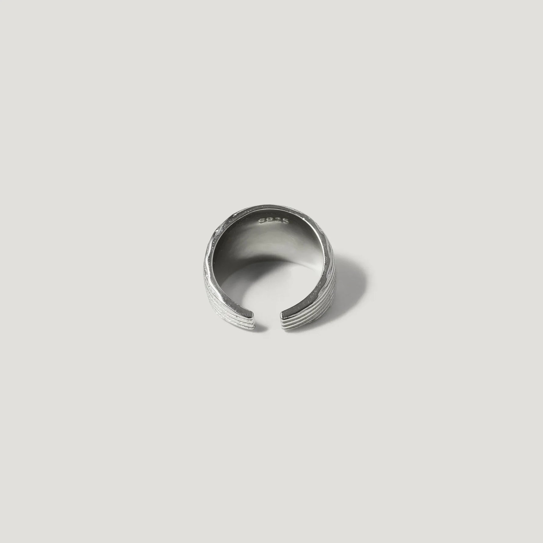Sterling silver open band ring with textured design on white background