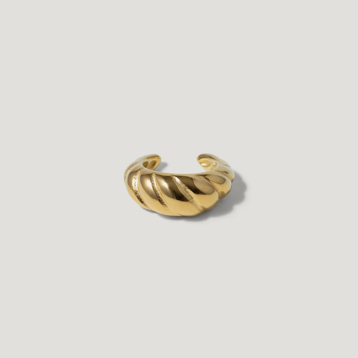 Chunky gold ear cuff with twisted rope design on white background