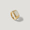 Gold signet ring with rectangular white stone center on neutral background