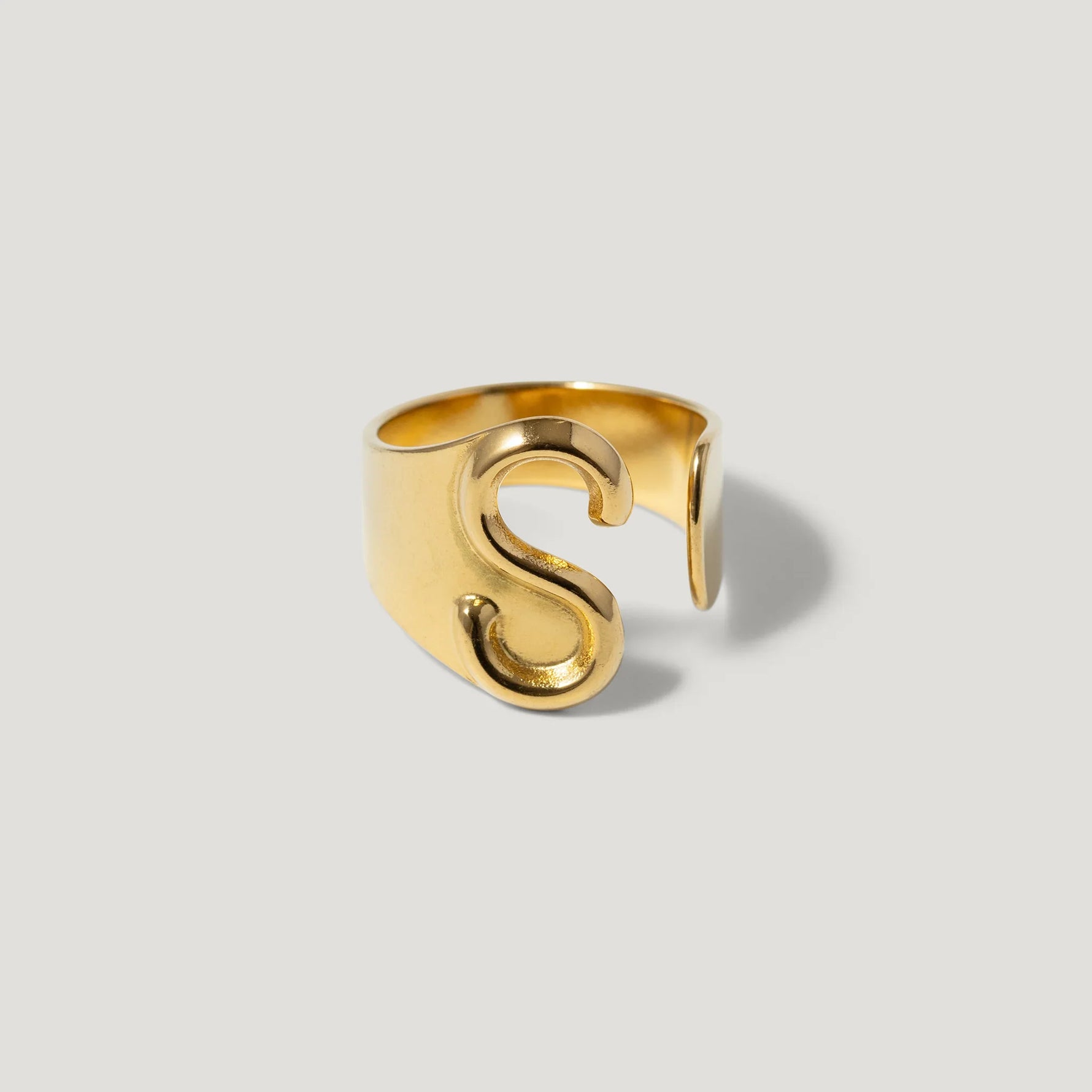 Gold adjustable ring with bold S initial on plain background, modern jewelry design