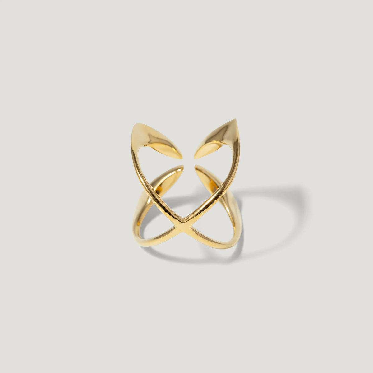 Modern open gold ring with sculptural, intersecting bands on a light background