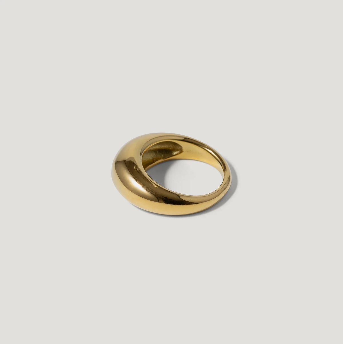 Bold gold dome ring with a smooth, polished finish on a light background