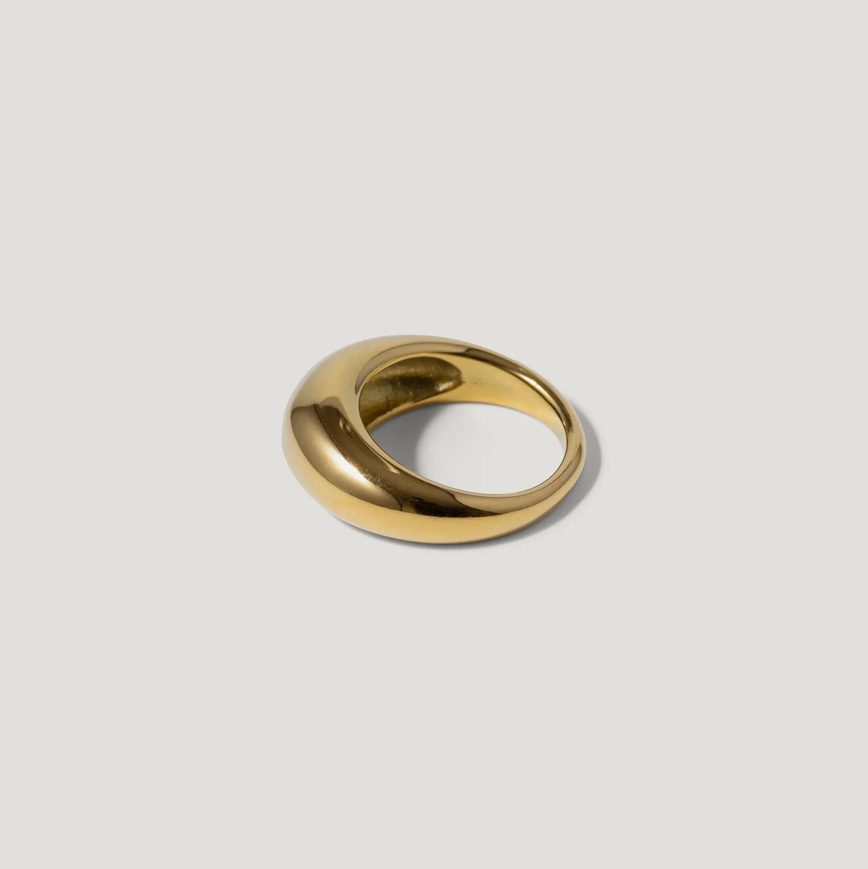 Bold gold dome ring with a smooth, polished finish on a light background