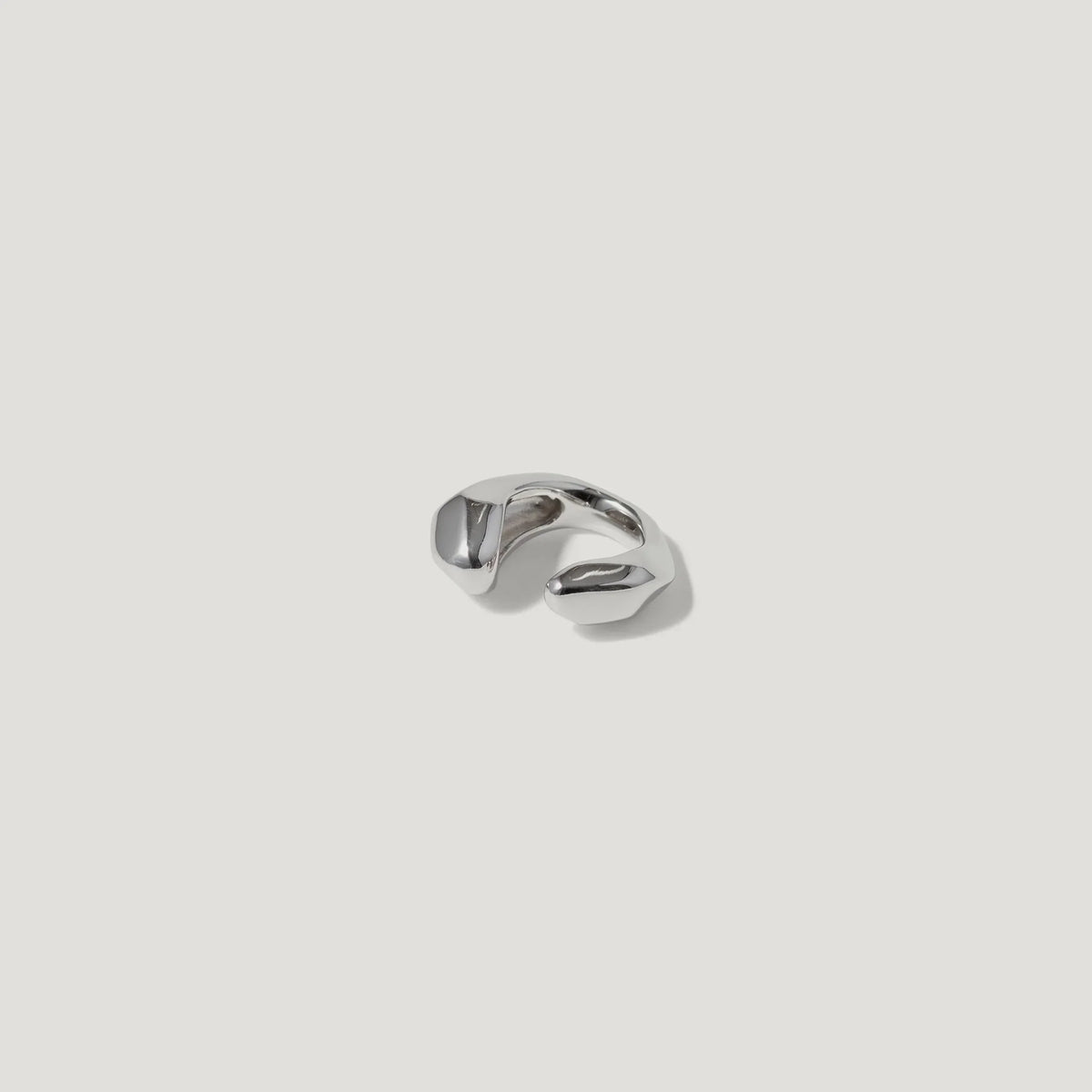 Abstract silver ring with organic, sculpted shape on white background