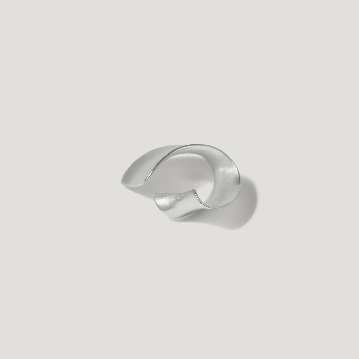 Sculptural silver cuff bracelet on a white background, modern jewelry design