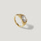 Gold ring with an oval clear gemstone set in a modern prong setting on white background.