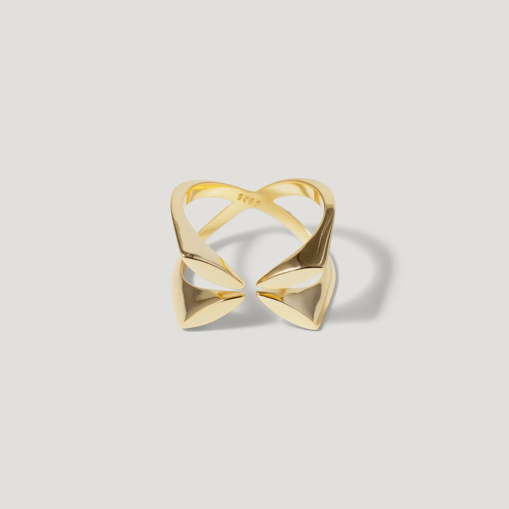 Geometric open gold ring with pointed ends on white background