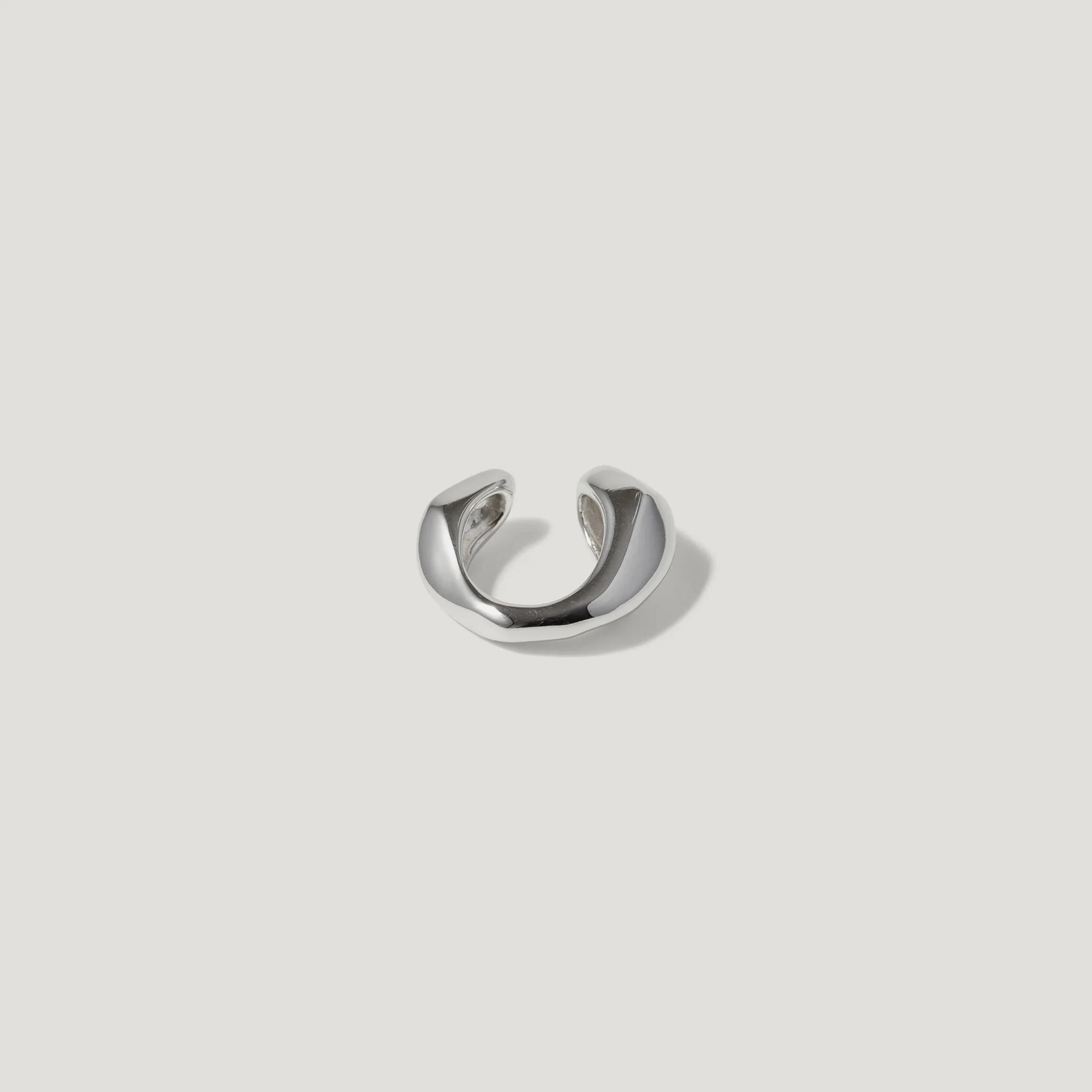 Minimalist silver ear cuff with smooth polished finish on white background