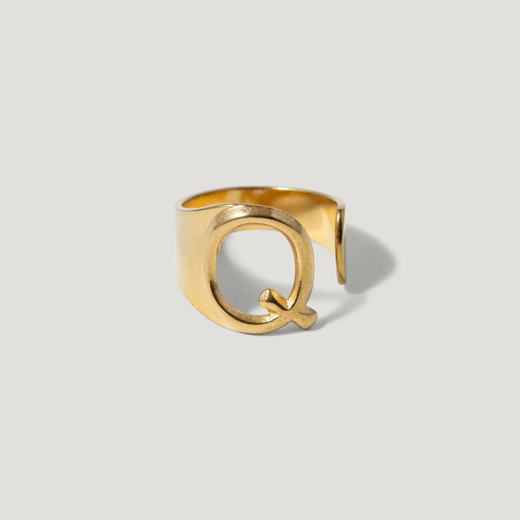 Gold adjustable ring with bold letter Q design on a light background