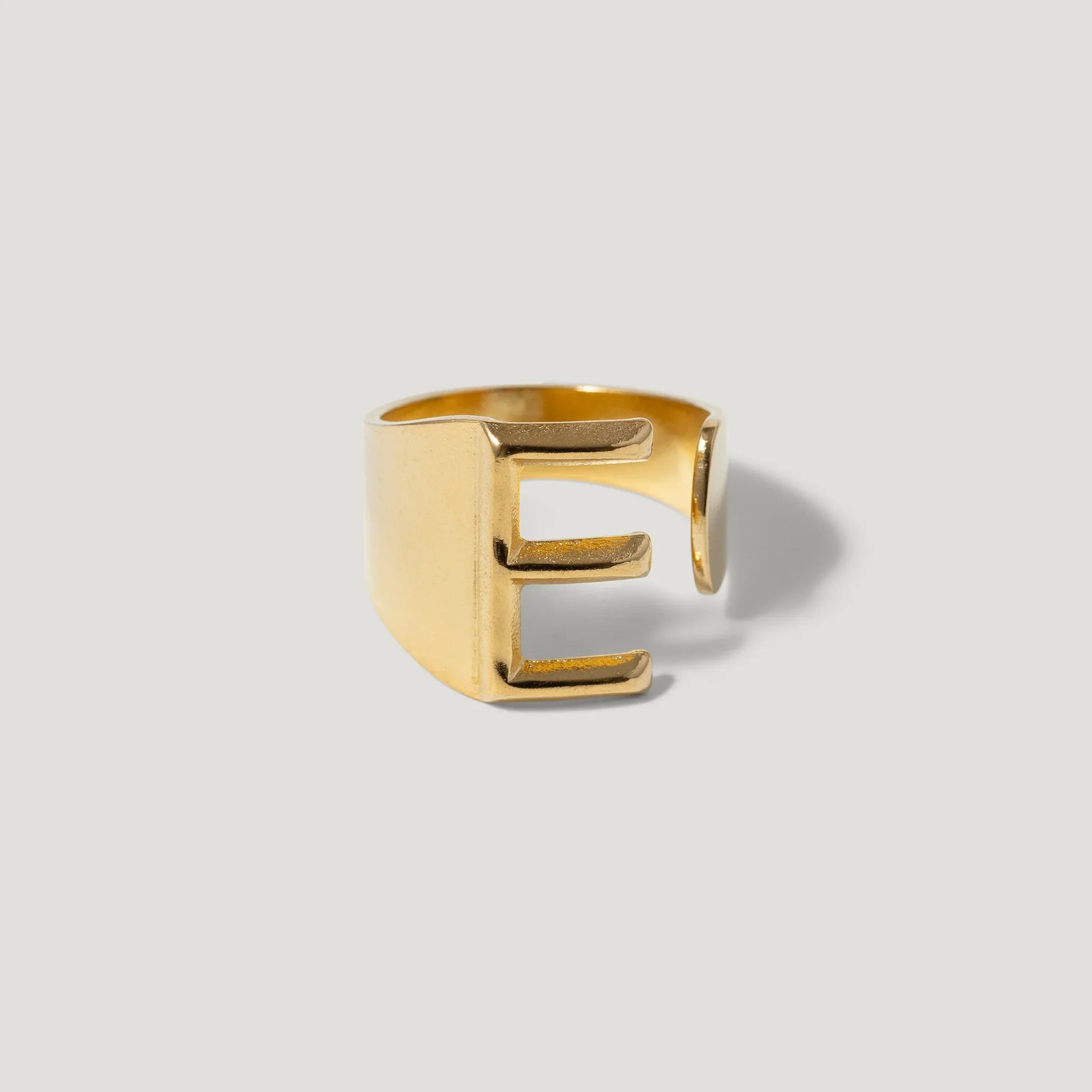 Gold letter E adjustable ring on plain light background