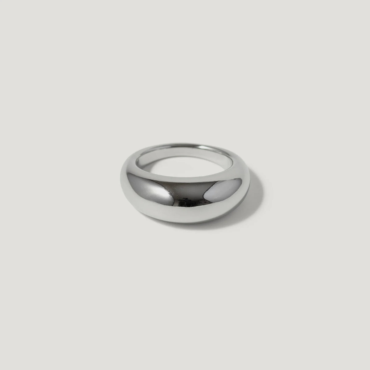 Polished silver dome ring on white background, minimalist jewelry design