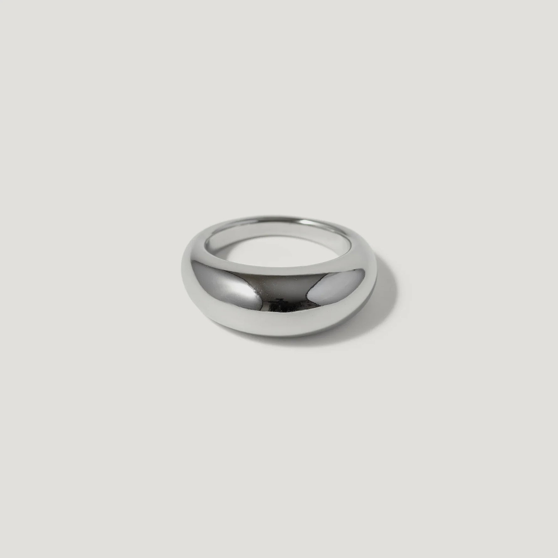 Polished silver dome ring on white background, minimalist jewelry design