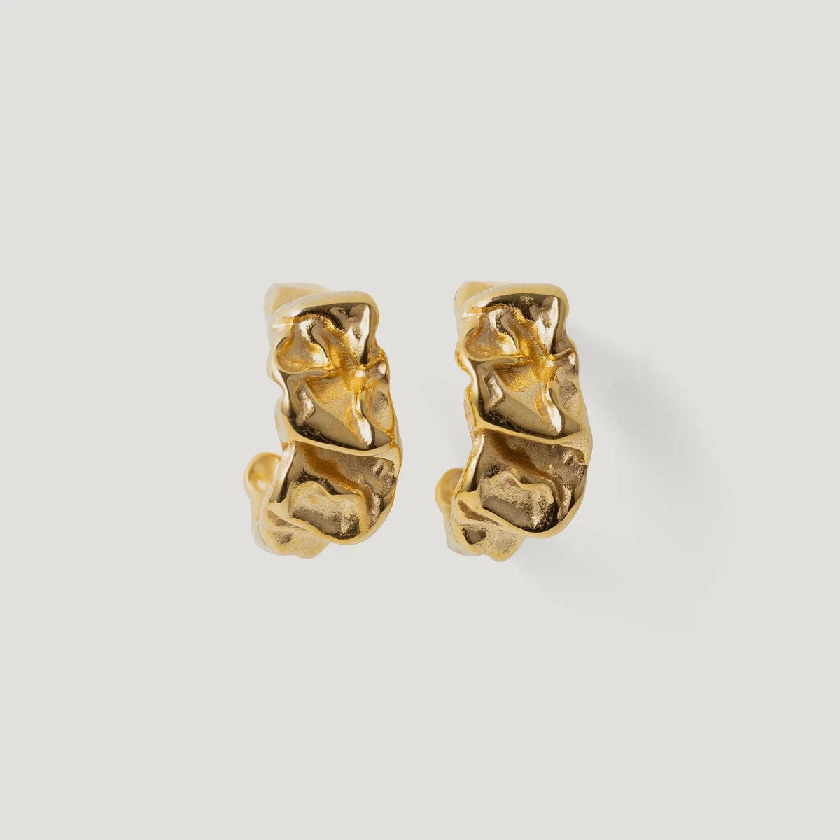 Pair of textured gold hoop earrings with organic, sculptural design on white background