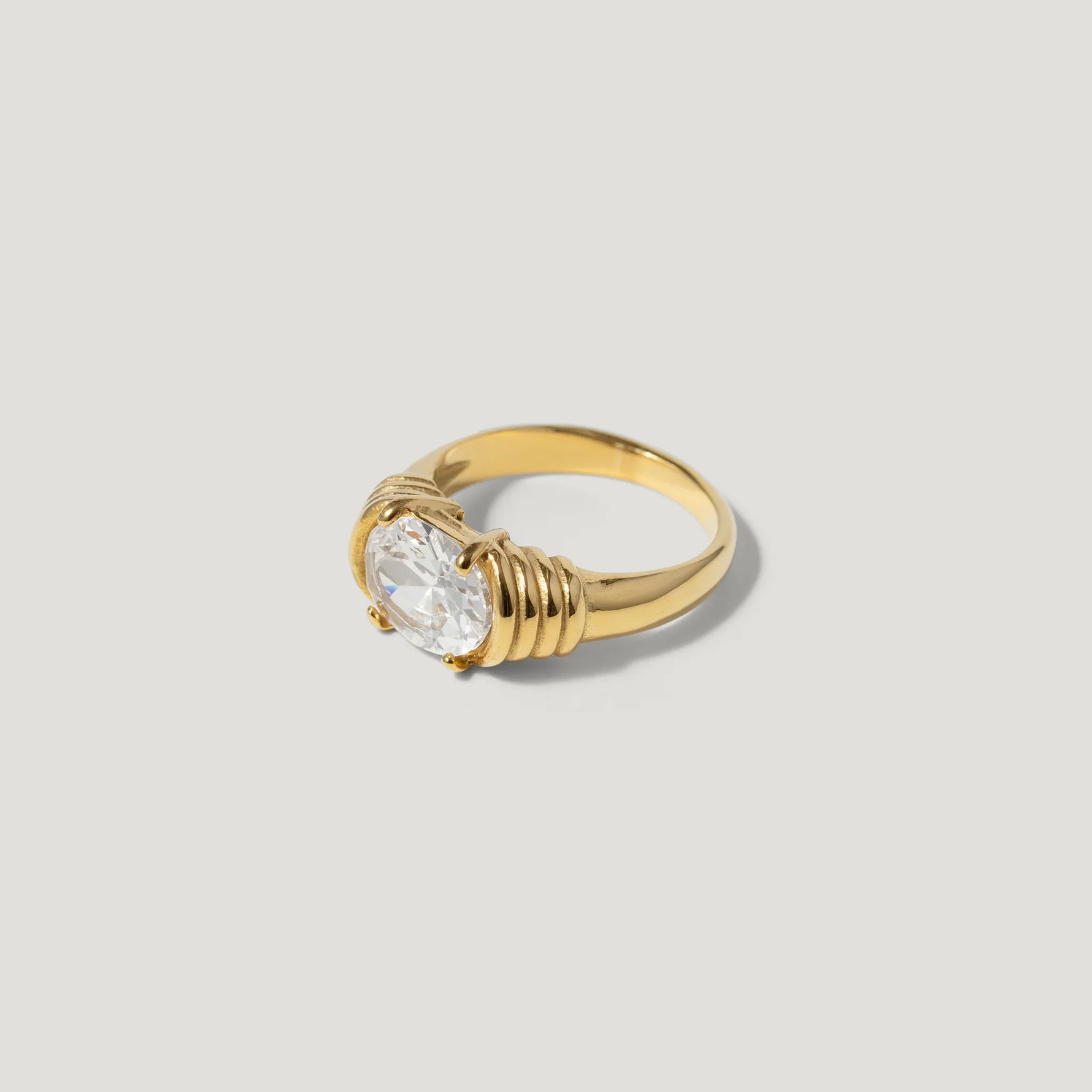 Gold ring with large oval clear gemstone on minimalist light background
