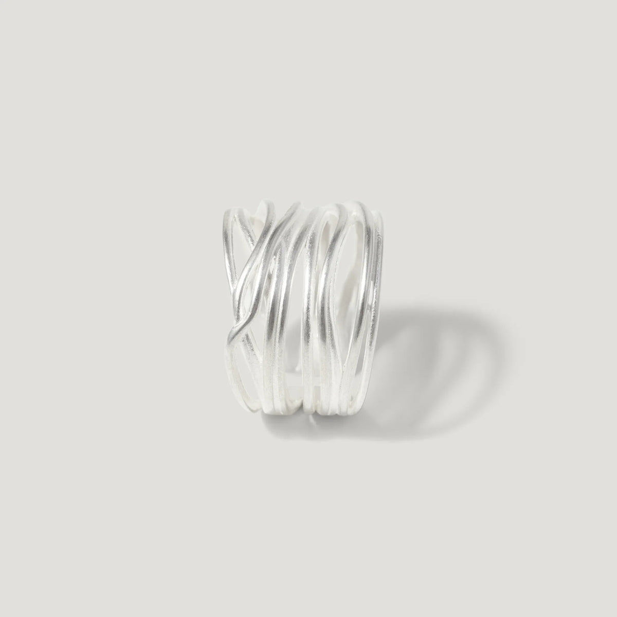 Modern sterling silver ring with layered, wavy bands on a plain light background
