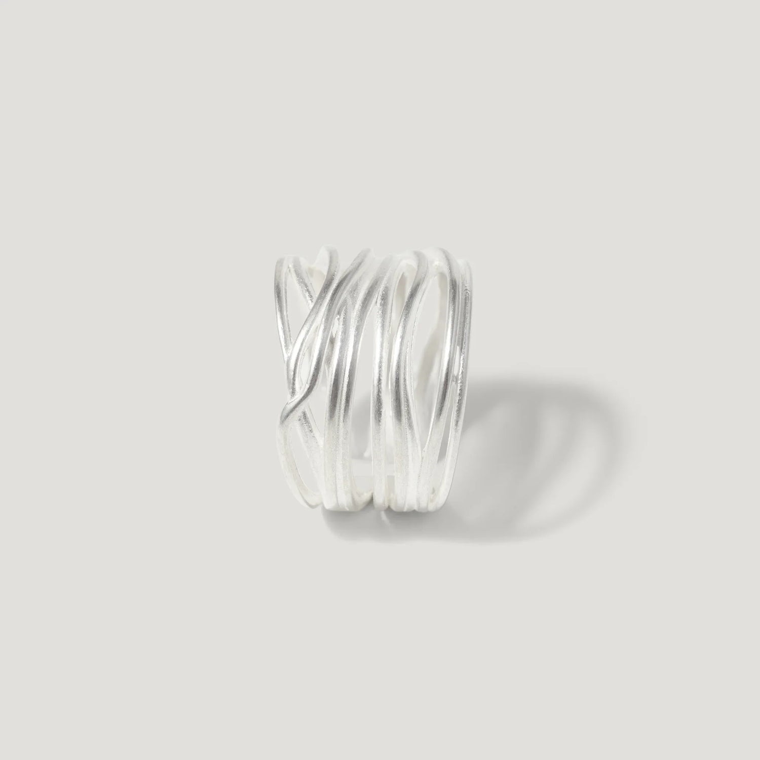 Modern sterling silver ring with layered, wavy bands on a plain light background