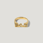Gold ring with bold DAD lettering on a plain background, personalized jewelry