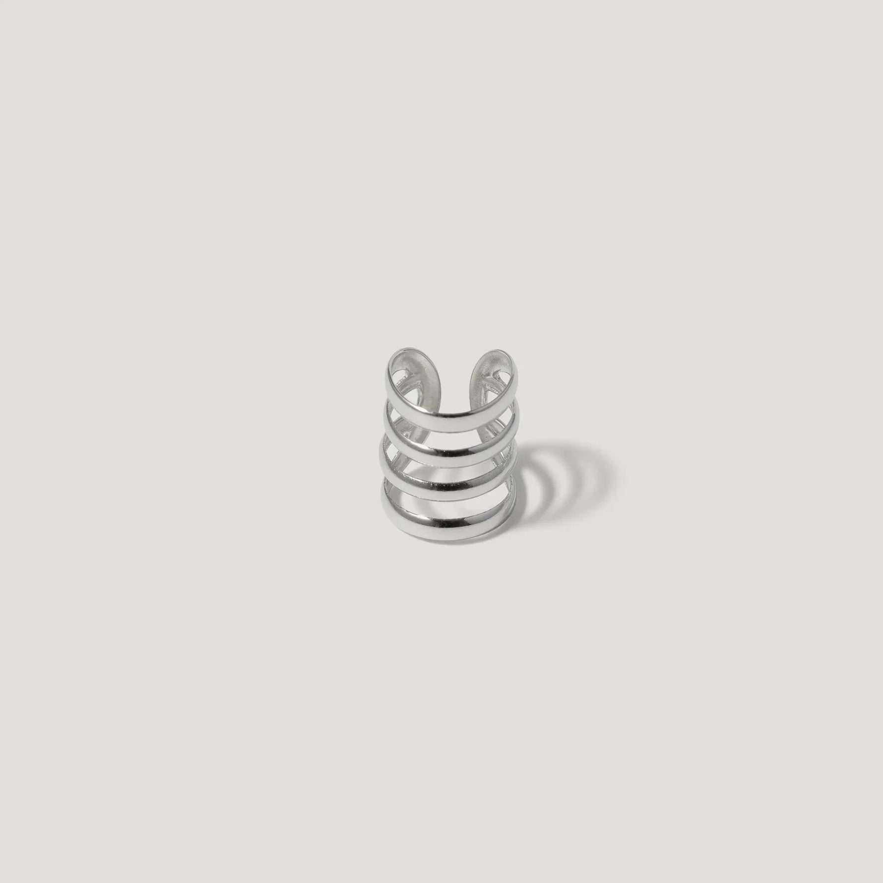 Minimalist silver ear cuff with four open bands on a white background