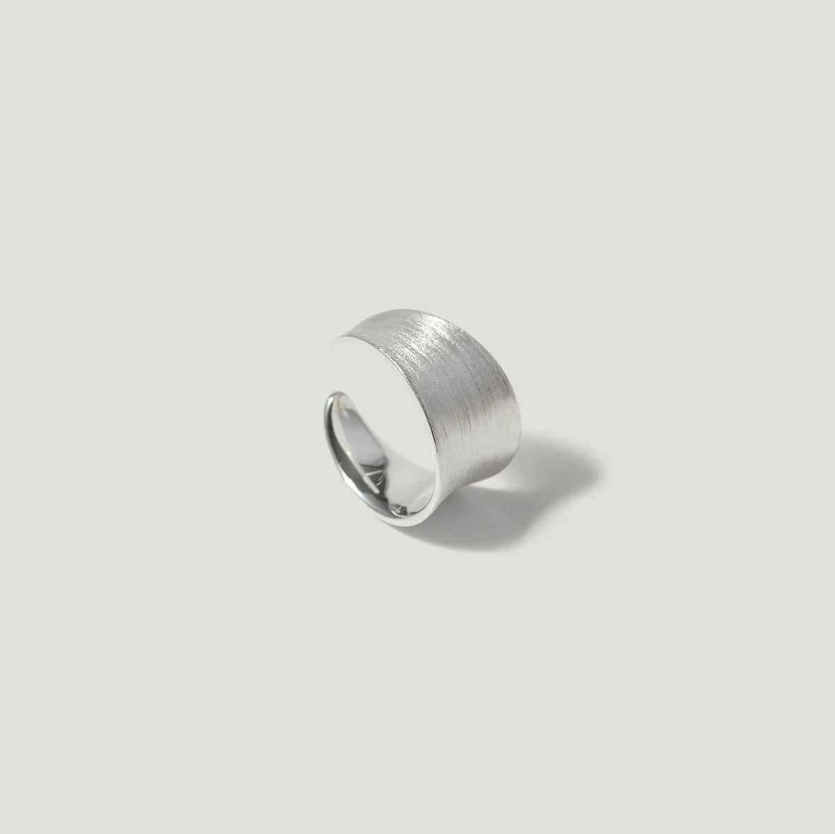 Wide brushed silver statement ring on light background
