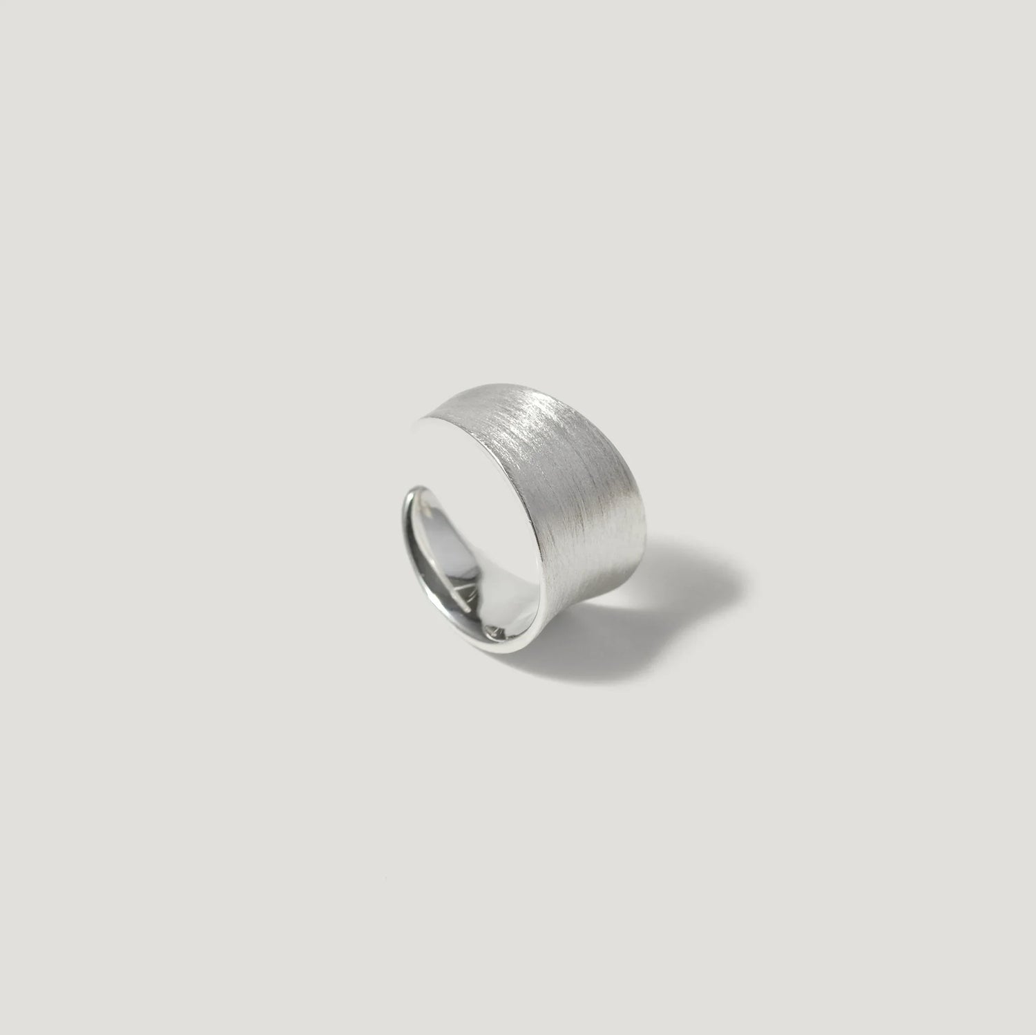 Wide brushed silver statement ring on light background