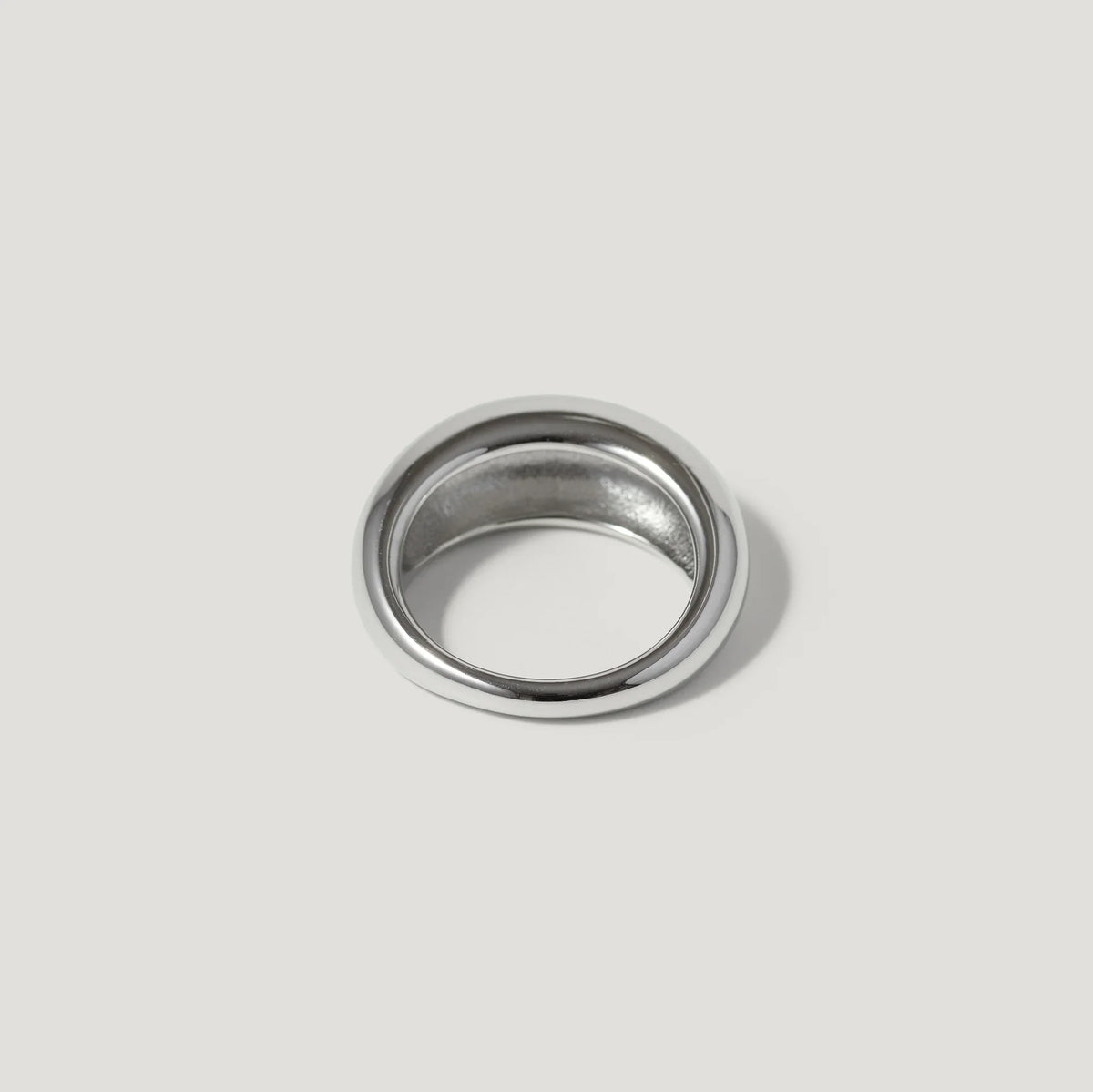 Polished silver dome ring with a smooth finish on a light grey background