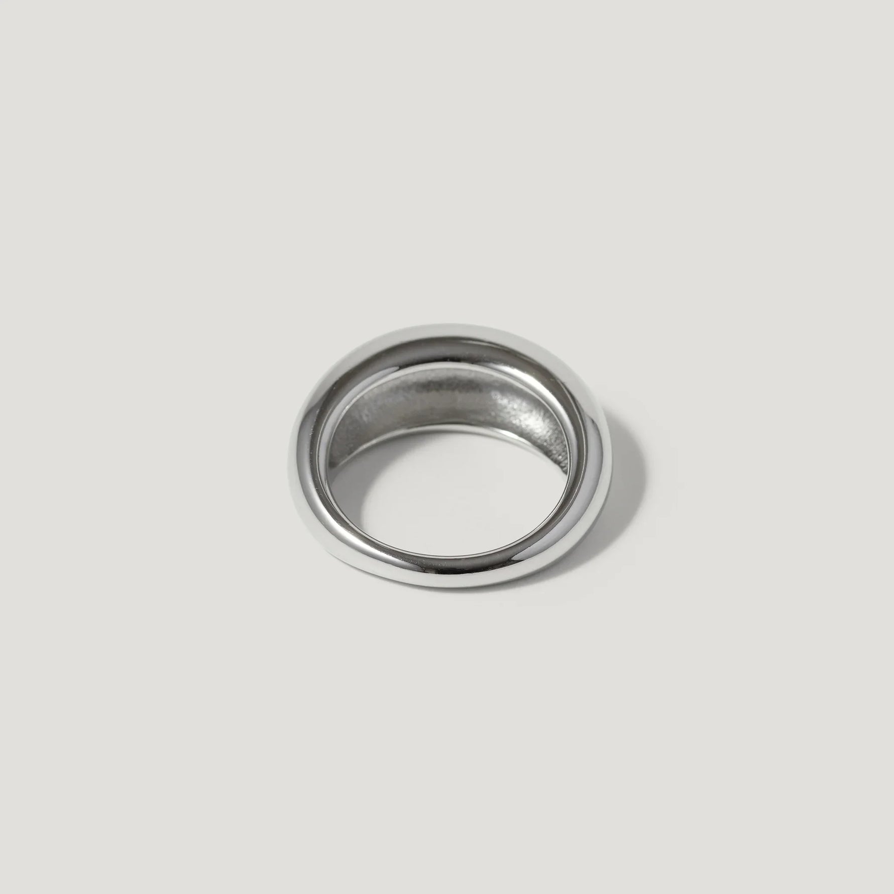 Polished silver dome ring with a smooth finish on a light grey background