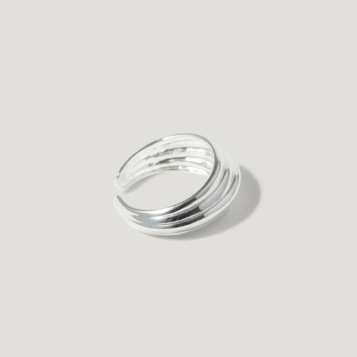 Chunky sterling silver ring with grooved texture on a plain light background