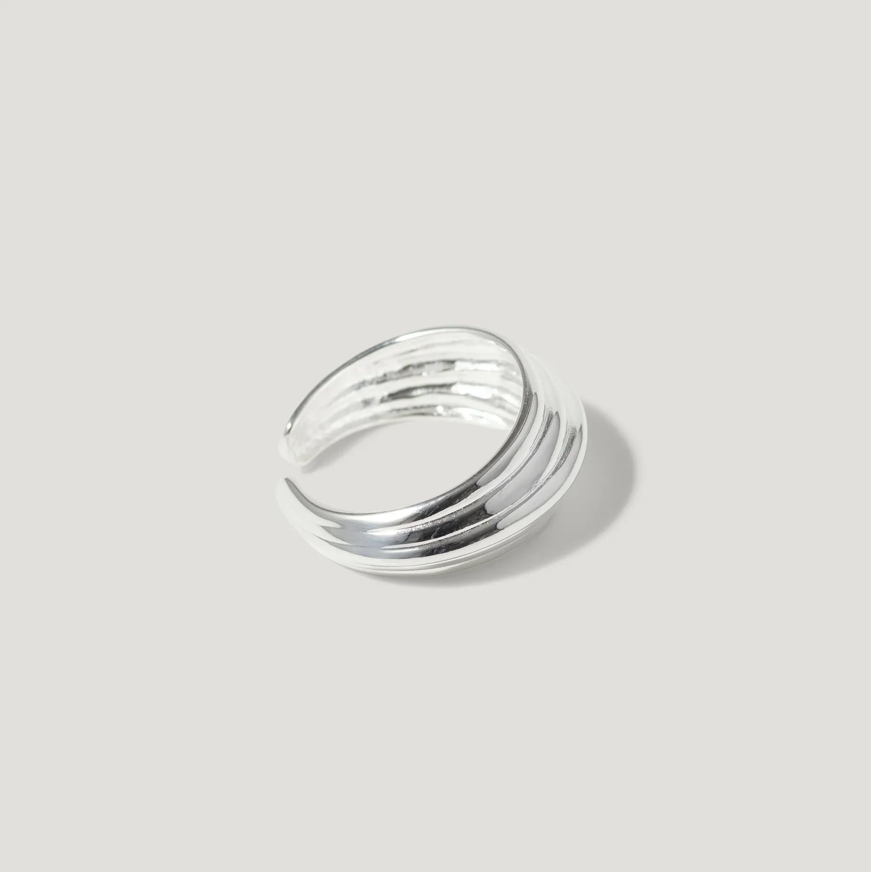 Chunky sterling silver ring with grooved texture on a plain light background