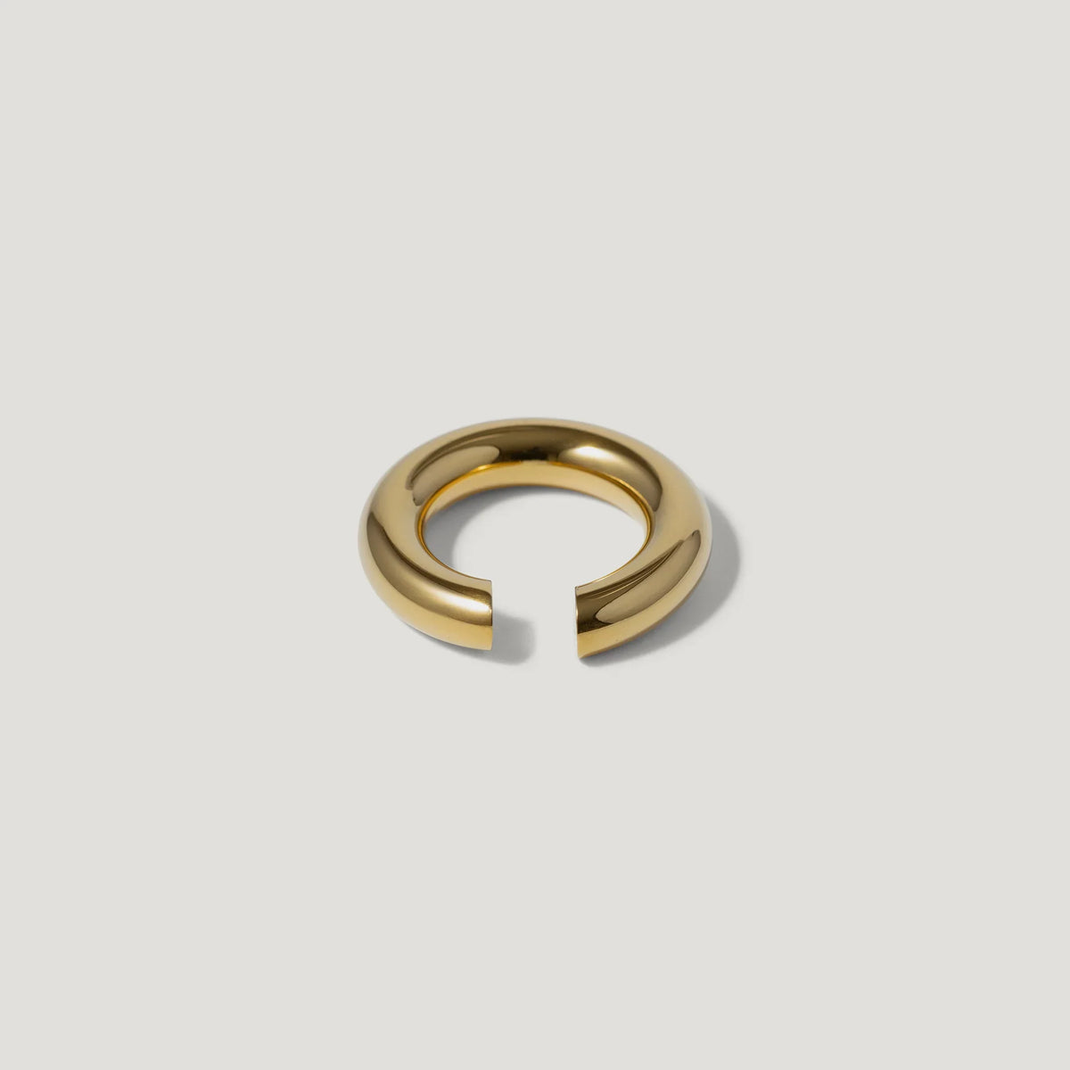 Minimalist gold open band ring on a plain light background