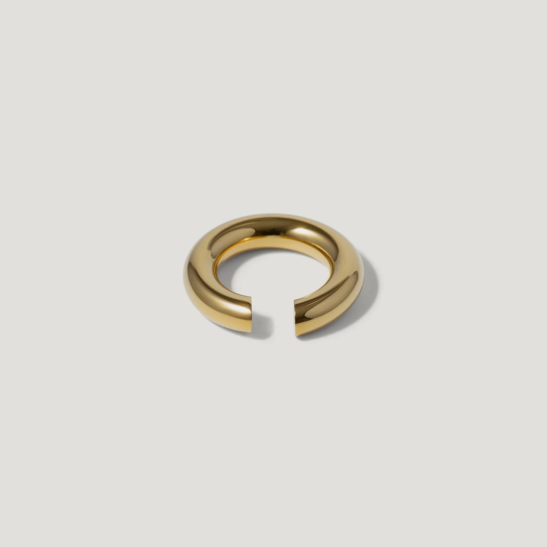 Minimalist gold open band ring on a plain light background