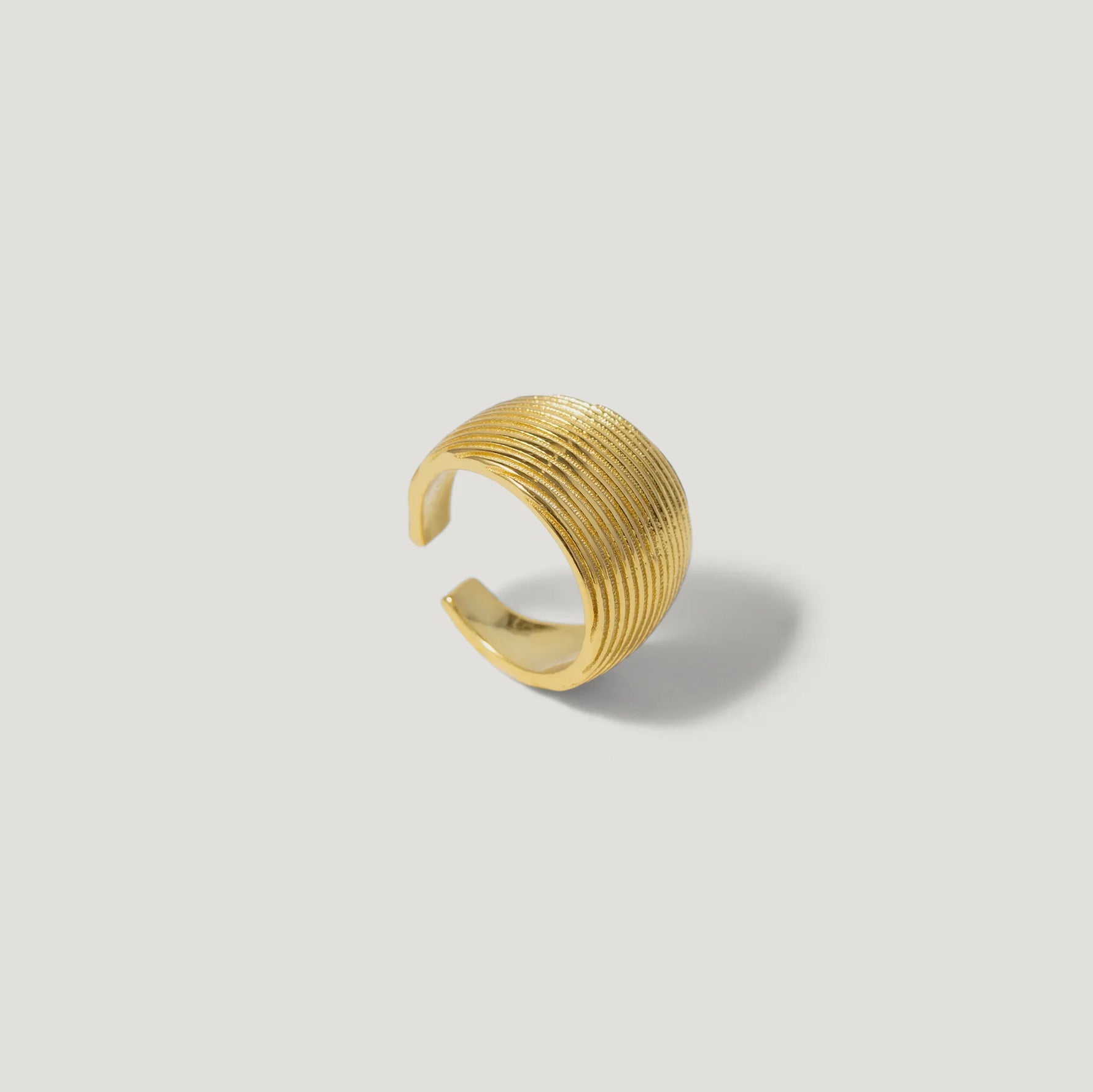 Textured gold adjustable ring with open band on a light background