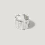Textured silver ring with a wavy, open-ended band on a plain light background