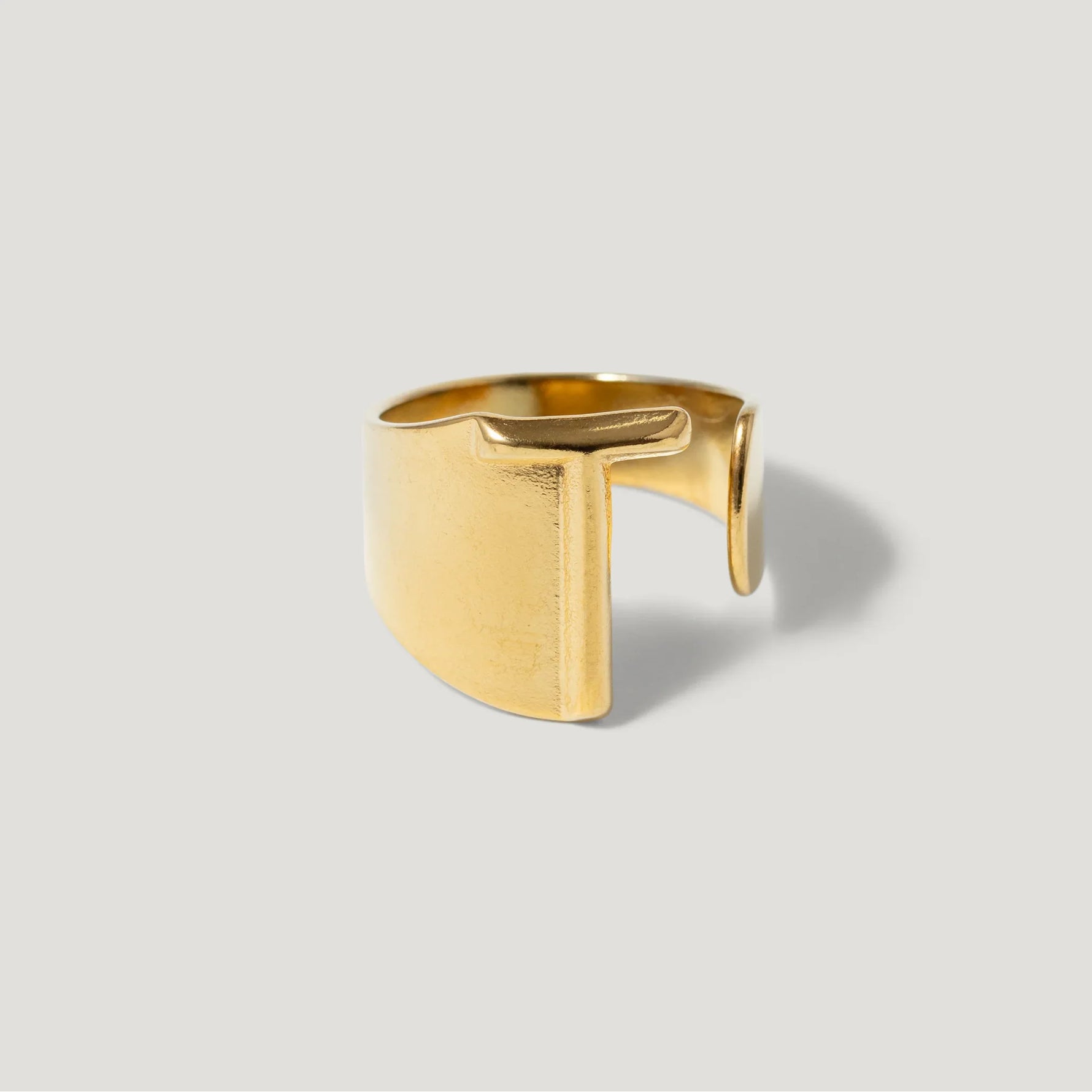 Modern gold open band ring with geometric cutout design on a light background